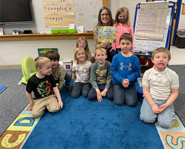 Happy kindergarten students enjoying story time with Superintendent Stanton